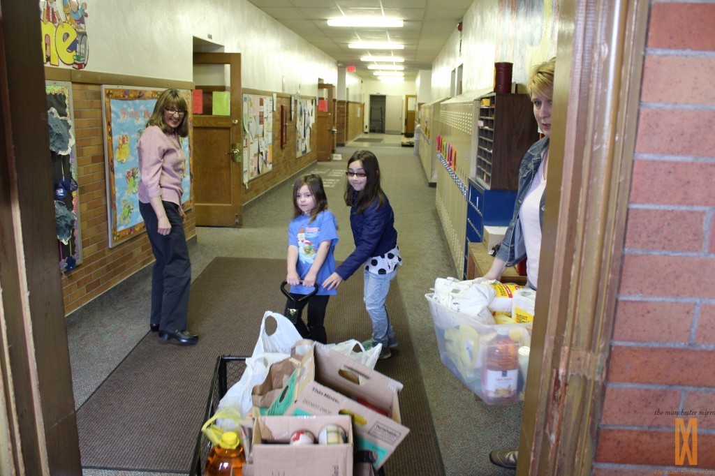 Abbi Austin and Emma Paxton haul in a wagon full of goodies while Mrs. Paxton carries in a full tub much to the delight of Laura Seyfried, Director of the Manchester Community Resource Center. 
