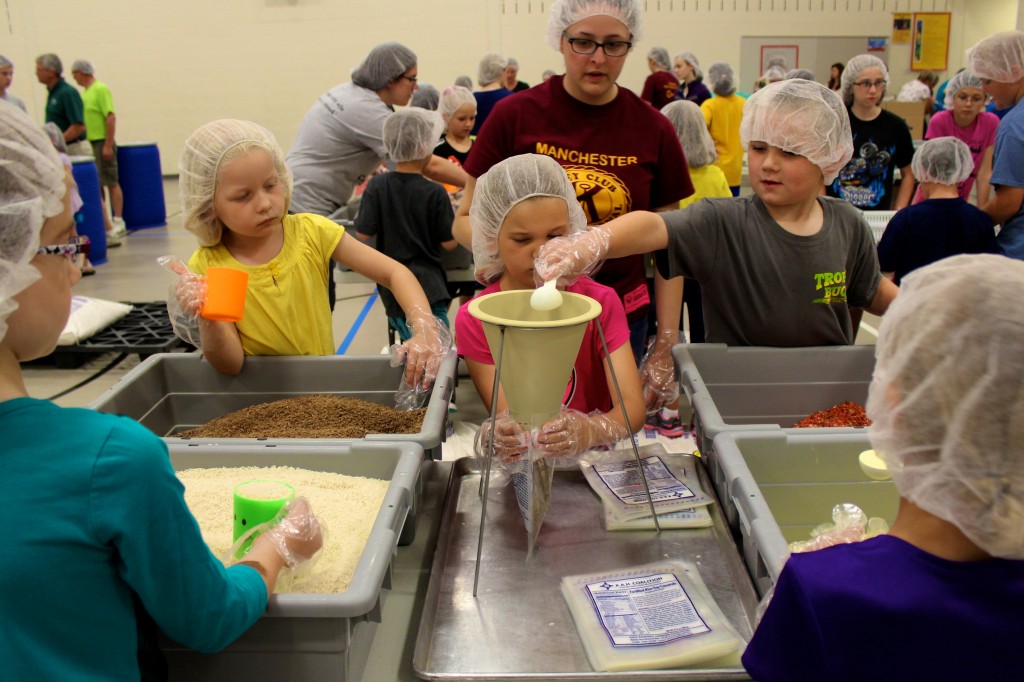 Anna Desbrough (in teal) scoops rice, while Aubrey Lauer (in purple) has the nutritional blend.