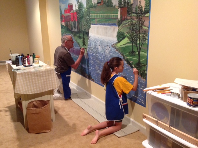 New Manchester resident, ____ Powell, formerly of Traverse City, is enjoying his home in Manchester, especially since he is only 20 minutes away from his only granddaughter, Emma. Papa Powell has painted a mural from a photo he took while in downtown Manchester. The photo above shows he and Emma, working on the mural in the Powell's basement. Mr. Powell has also purchased a 1931 Model A to drive in future Manchester parades. "They are definitely fitting in quite nicely!" says his daughter in law (Emma's mom), Laurie Powell of Ann Arbor.